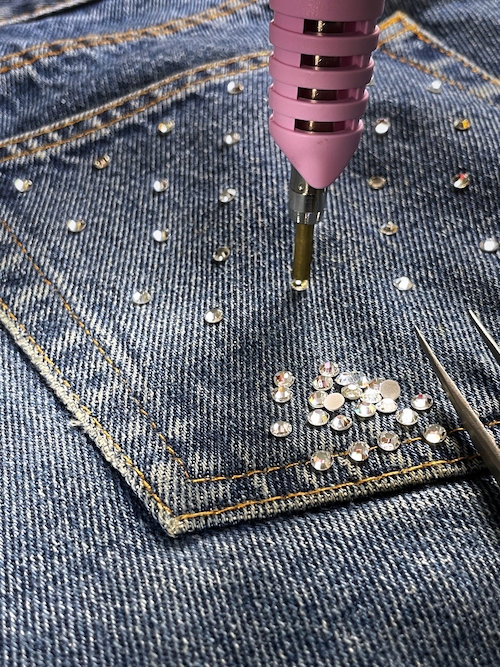Photo d'un applicateur à strass qui fixe des strass hotfix sur un jean