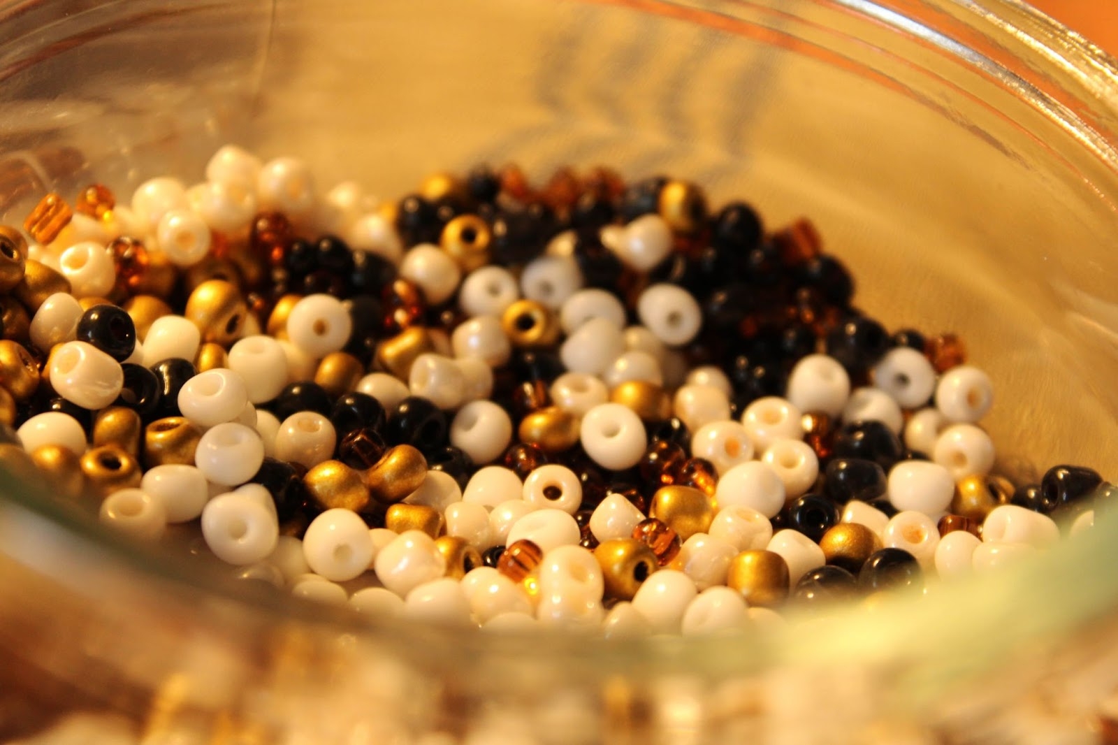 Illustration de perles blanches, noires et dorées dans un bocal.